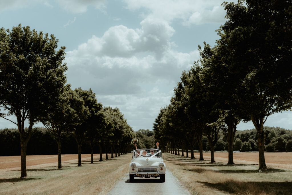 Wedding couple driving through Badminton Estate 